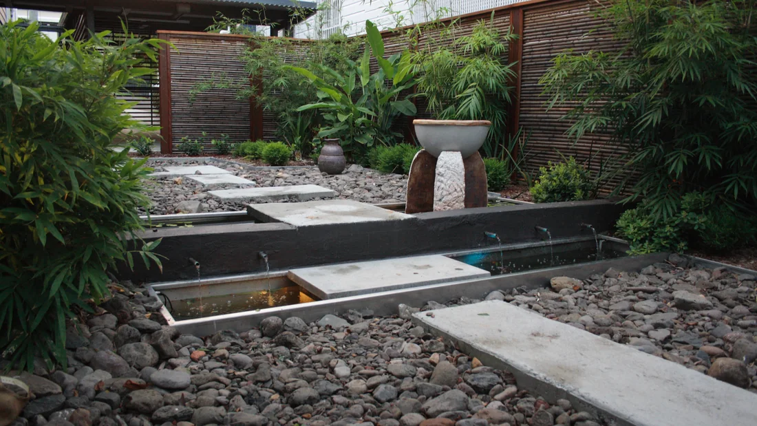 Sandstone crazy paving path curving between sandstone boulders, timber posts and a wrought iron screen