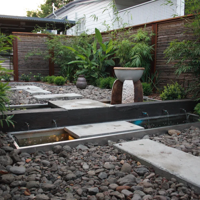 Timber-framed bamboo screens enclosing a courtyard of water rills and river stone