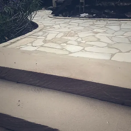 Crazy paving finishing against a sawn stone step and a smooth paved landing