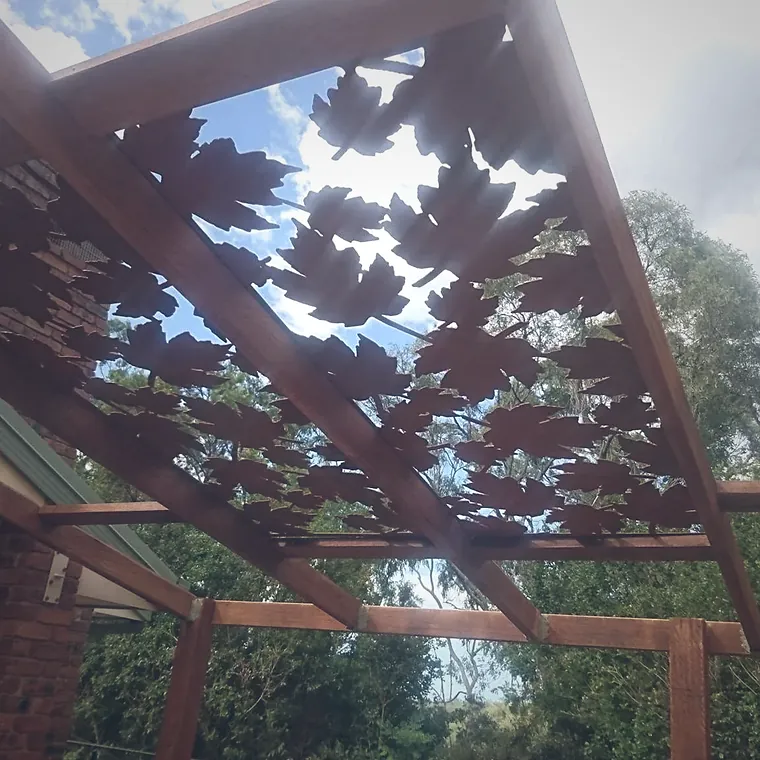 Laser-cut Corten steel leaf screen set into a hardwood pergola against the sky