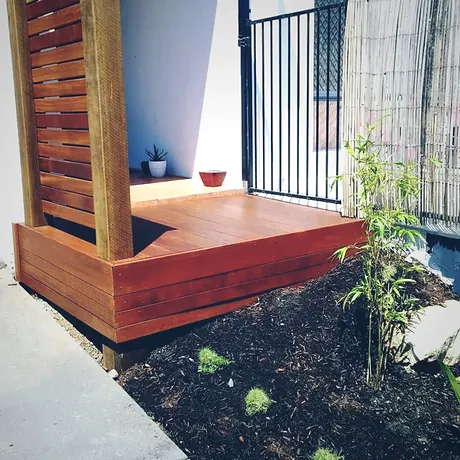 Raised hardwood platform daybed built against a timber batten screen