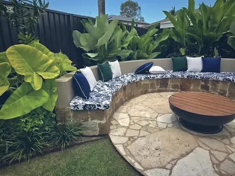 Crazy paved fire pit circle enclosed by a curved sandstone bench seat