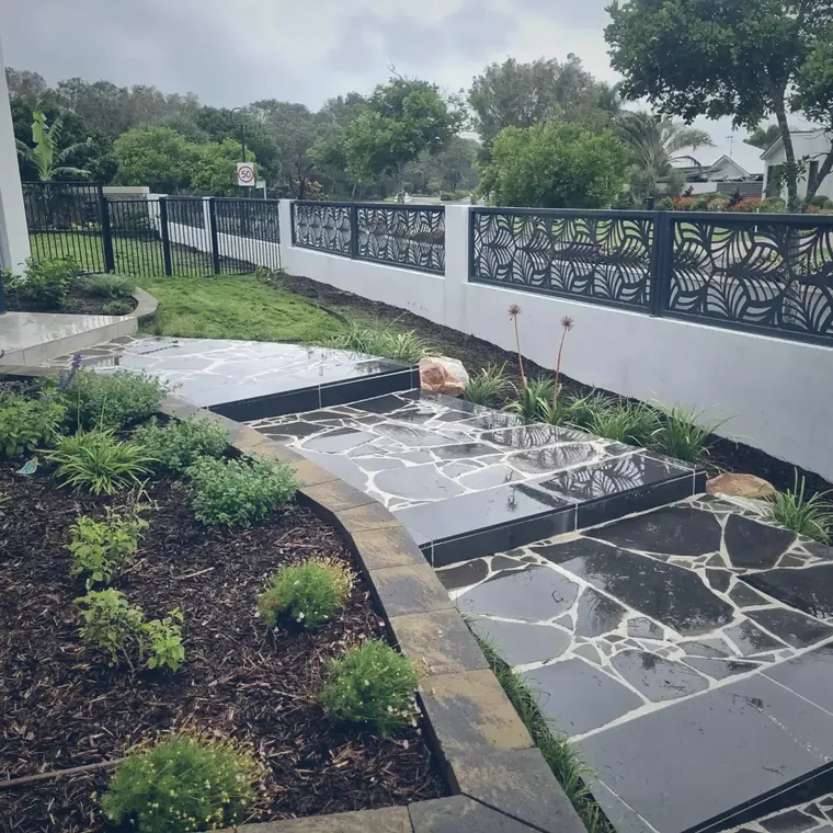 Stone paving path beside a white rendered wall fitted with decorative screen panels