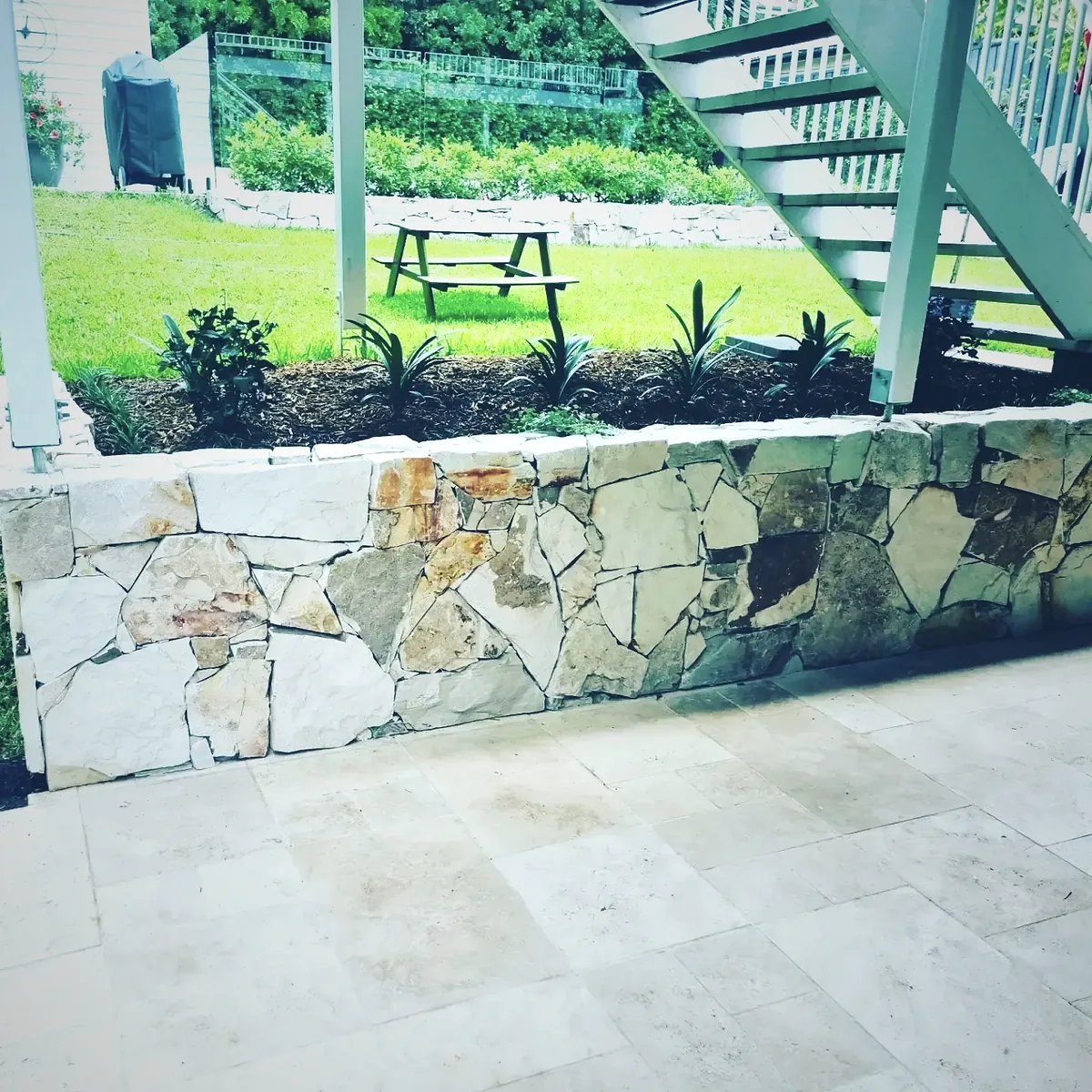 Limestone and sandstone feature wall above travertine paving