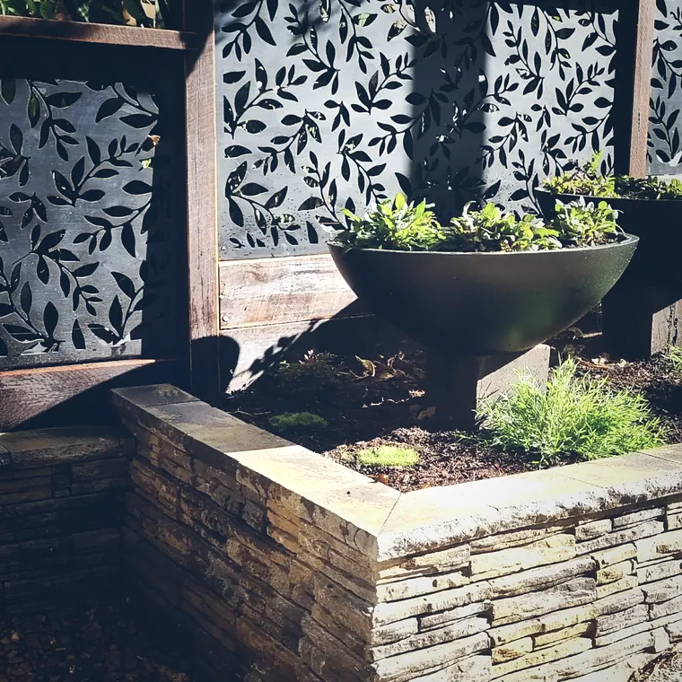 Laser-cut screen panels standing over a sleeper retaining wall and fire bowl