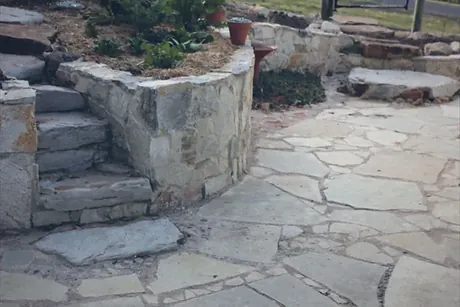 Sandstone crazy paving across a terrace and down steps, held by matching natural stone retaining